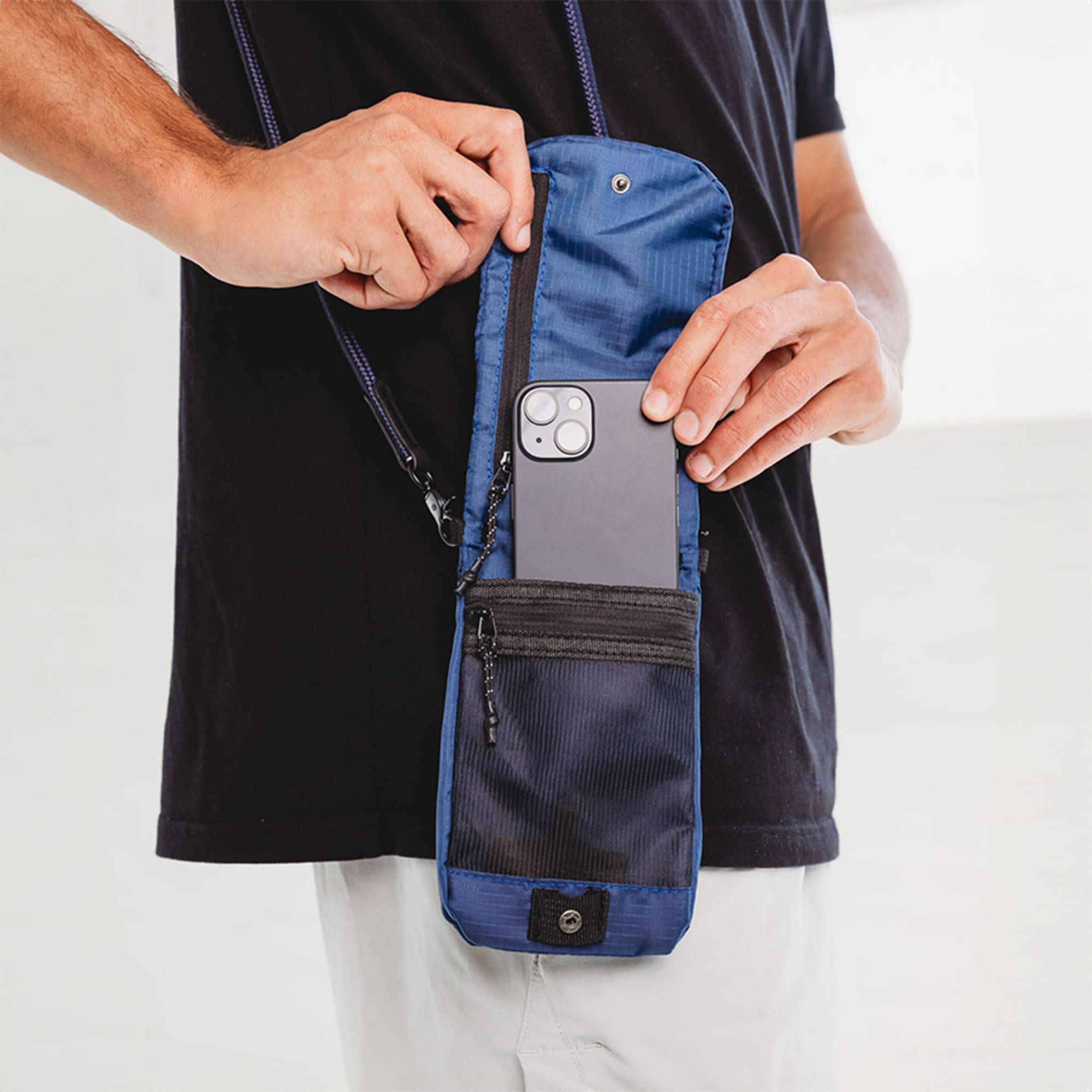 A navy blue ripstop water-resistant pouch being held, with a smartphone partially inserted and a zippered compartment visible.