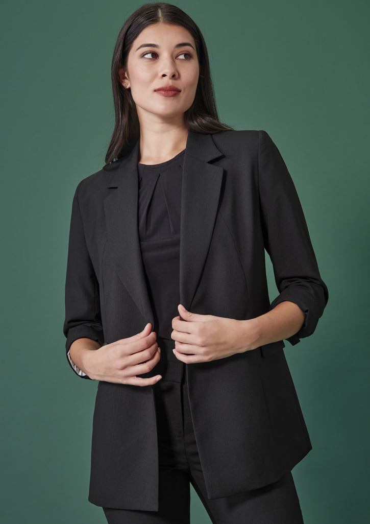 A black double-breasted longline jacket with rolled sleeves, set against a green background.