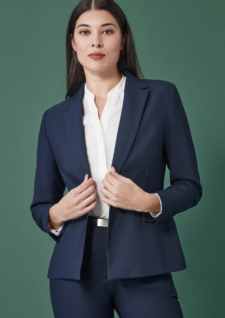 A navy single-button mid-length jacket with a tailored fit, styled with a white blouse. Features branding on the jacket.