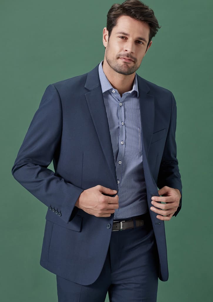 A navy men's jacket, tailored with a slim fit, worn over a striped shirt against a green background.