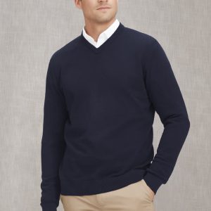 A knitted navy jumper featuring a v-neck design and a ribbed hem, worn by a model with a neutral background.