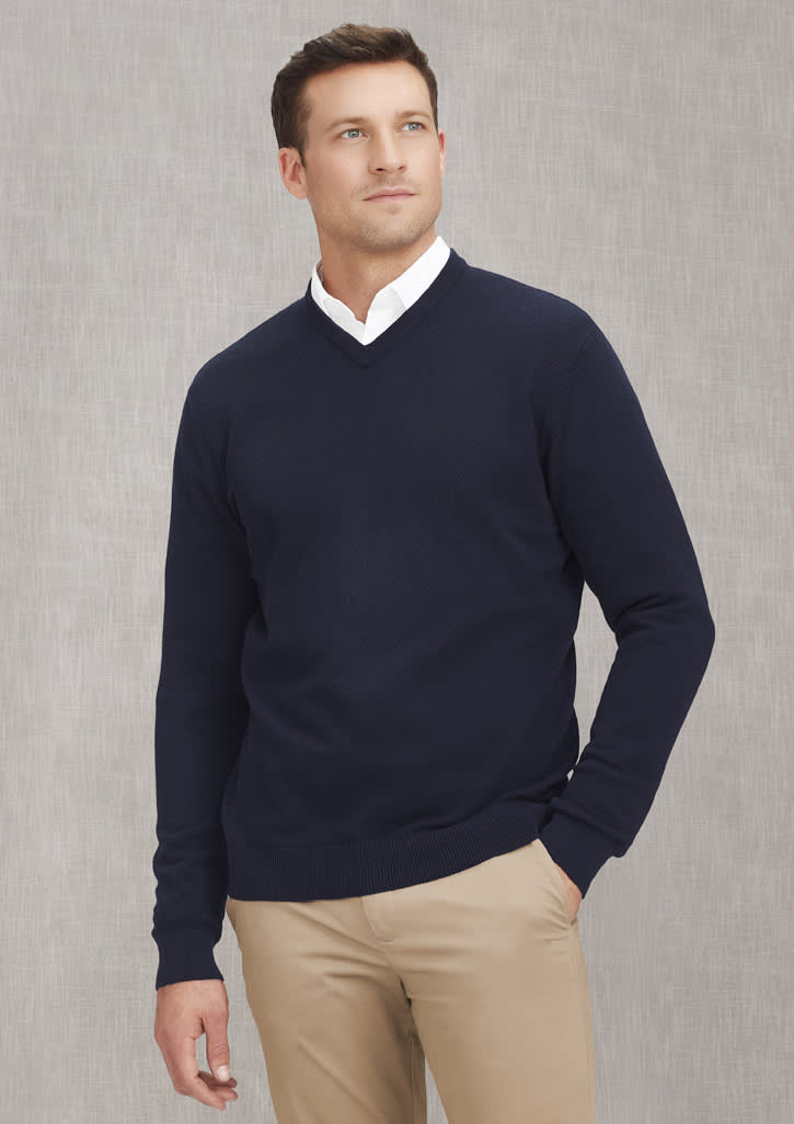 A knitted navy jumper featuring a v-neck design and a ribbed hem, worn by a model with a neutral background.