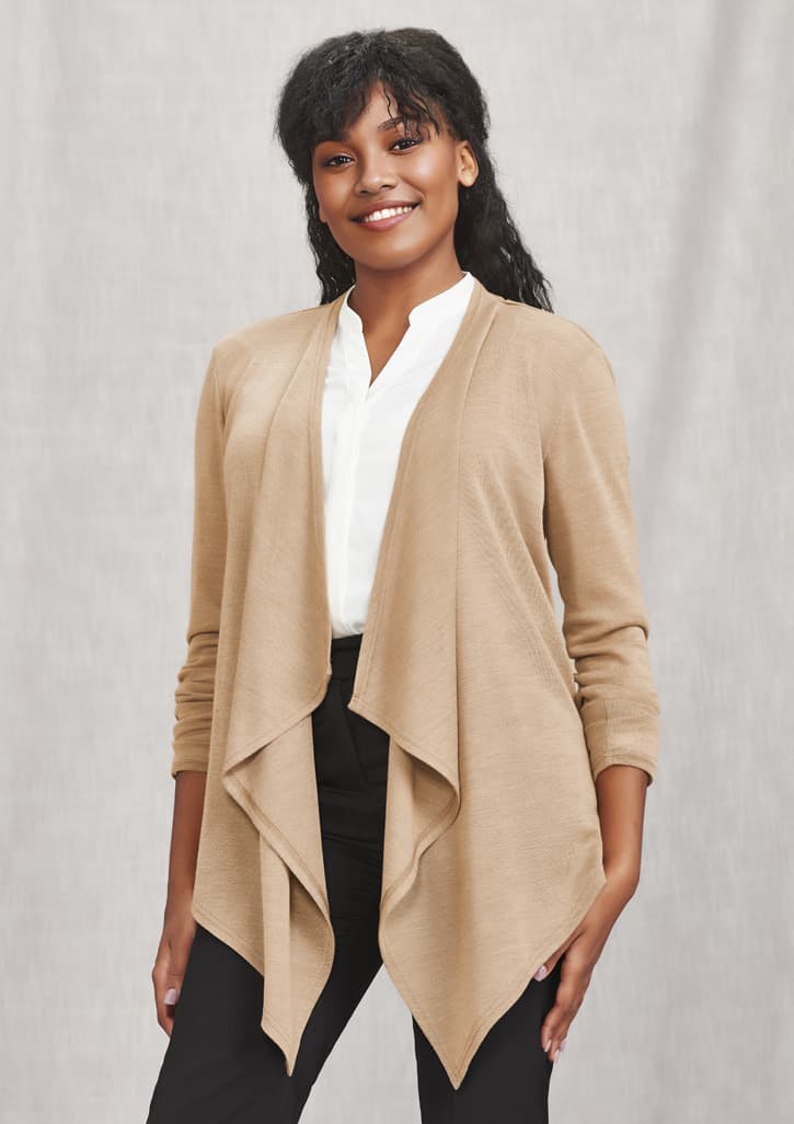 A woman wearing a beige waterfall cardigan over a white blouse and black trousers, smiling at the camera.