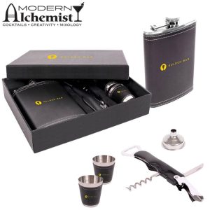 A drink bottle gift set featuring a black flask, two silver cups, a funnel, a corkscrew, and a branded box.