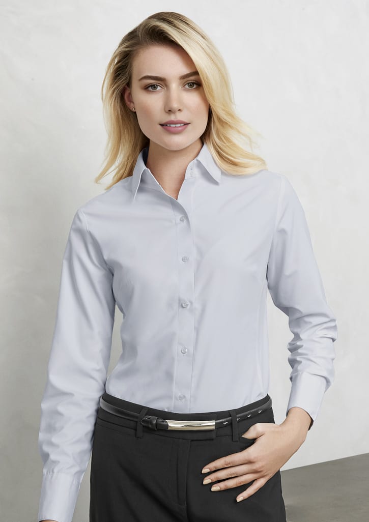 A light blue long sleeve button-up shirt for women, featuring a collar and fitted silhouette. It has a logo on it.