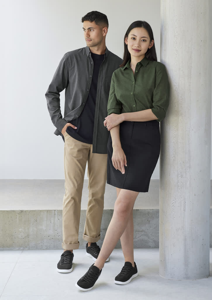 A grey button-up shirt on a man and a green button-up shirt on a woman, both paired with casual trousers and sneakers.