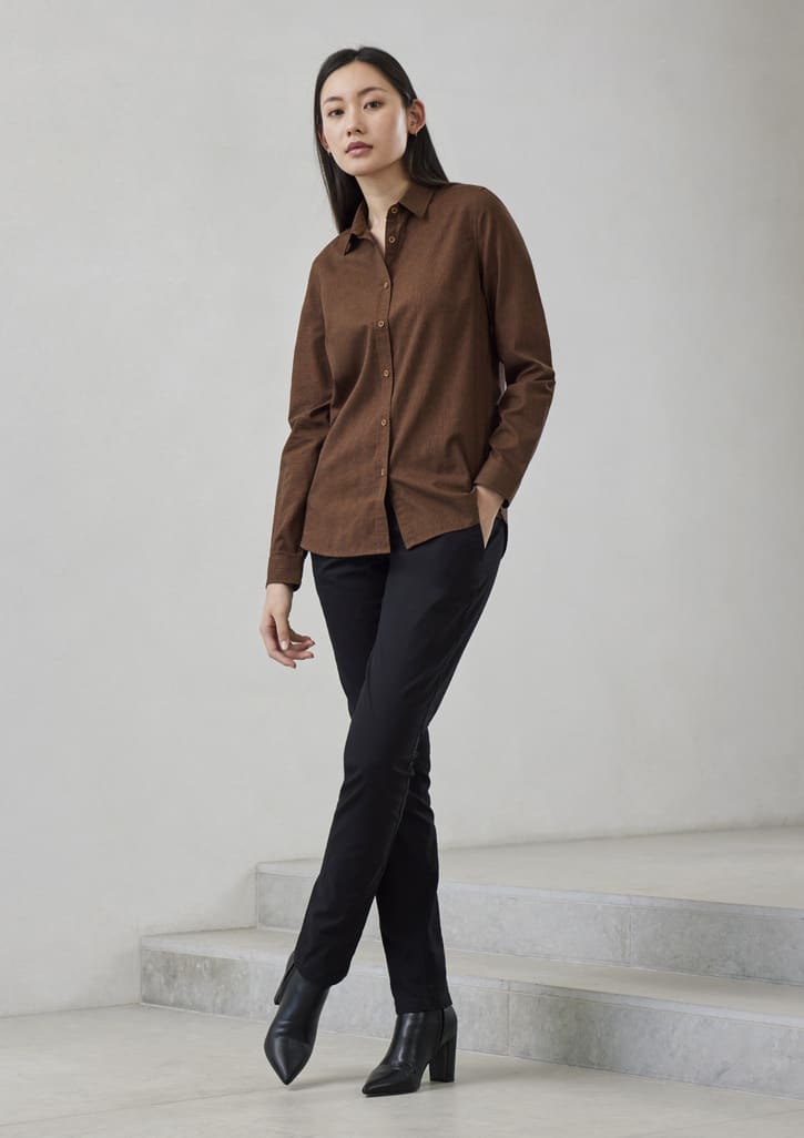 A brown long sleeve button-up shirt paired with black trousers, modelled by a woman standing on a staircase.