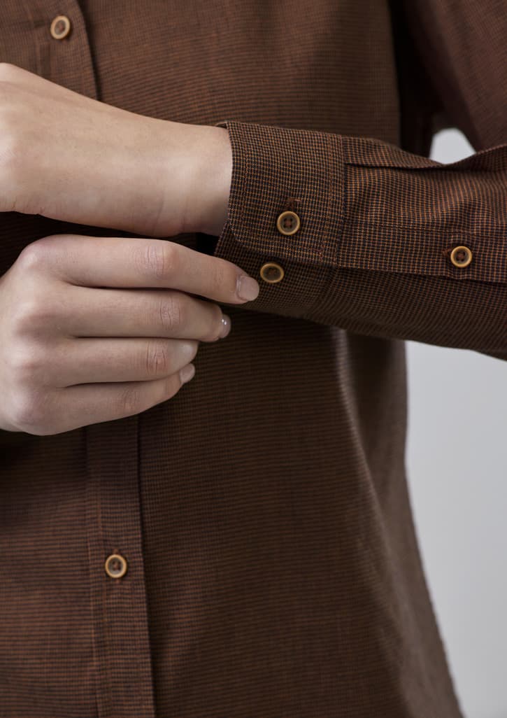 A brown button-up long sleeve shirt with a patterned texture and contrasting buttons on the cuffs.