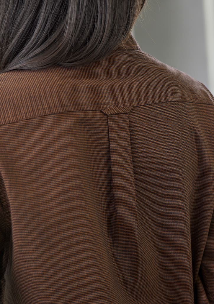 A brown long sleeve shirt featuring a button-up design and a logo on the back.