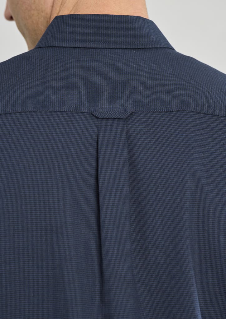A navy long sleeve shirt with a button-up collar and a back pleat, featuring a subtle check pattern.