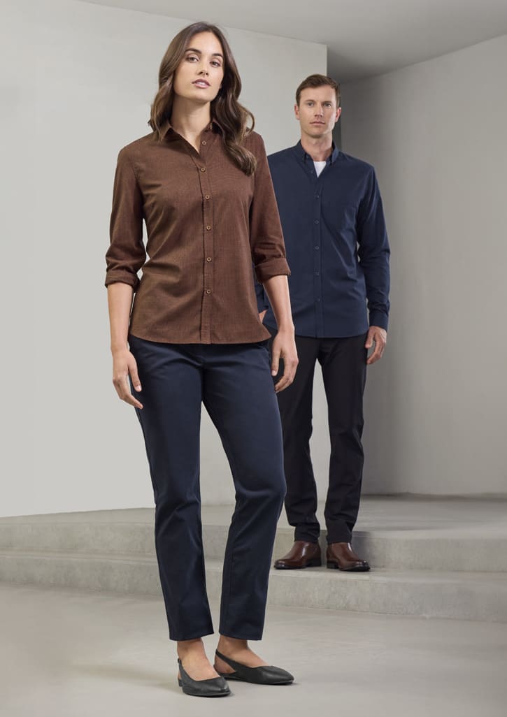 A brown long sleeve button-up shirt worn by a woman, paired with dark trousers; a man in a navy shirt stands behind.