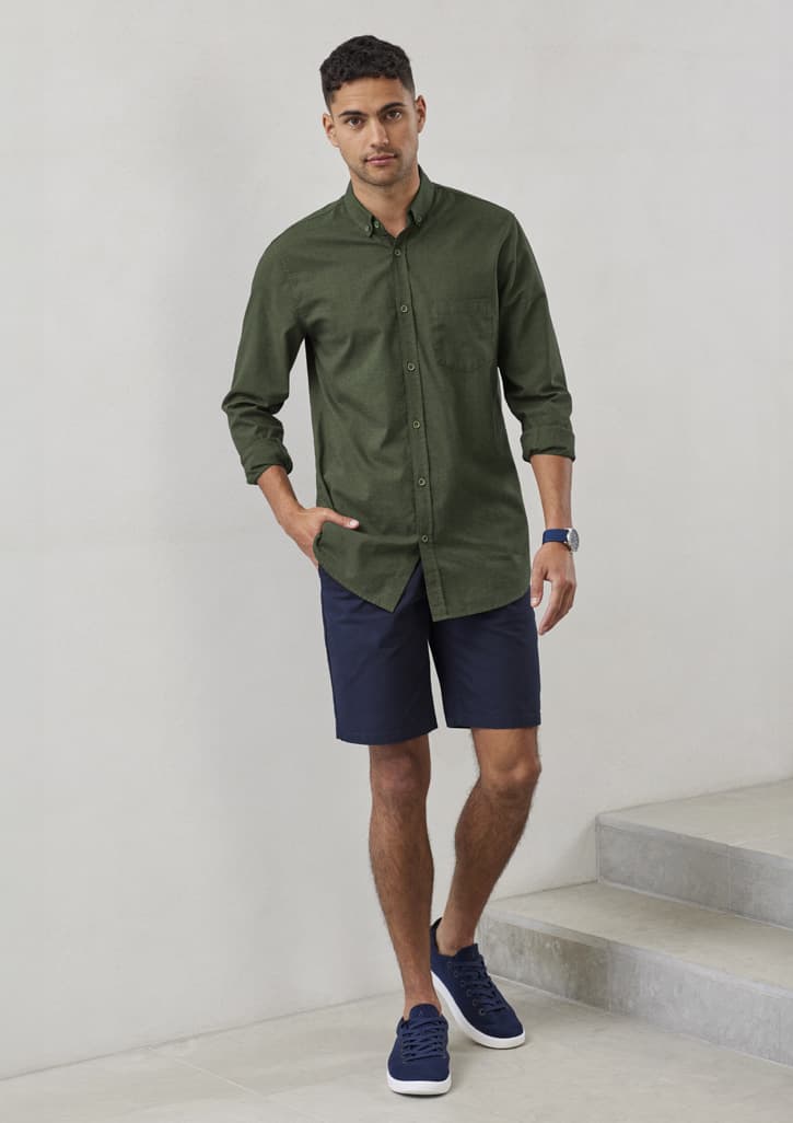 A men's button-up long sleeve shirt in olive green, paired with navy shorts and casual shoes, displayed against a plain background.
