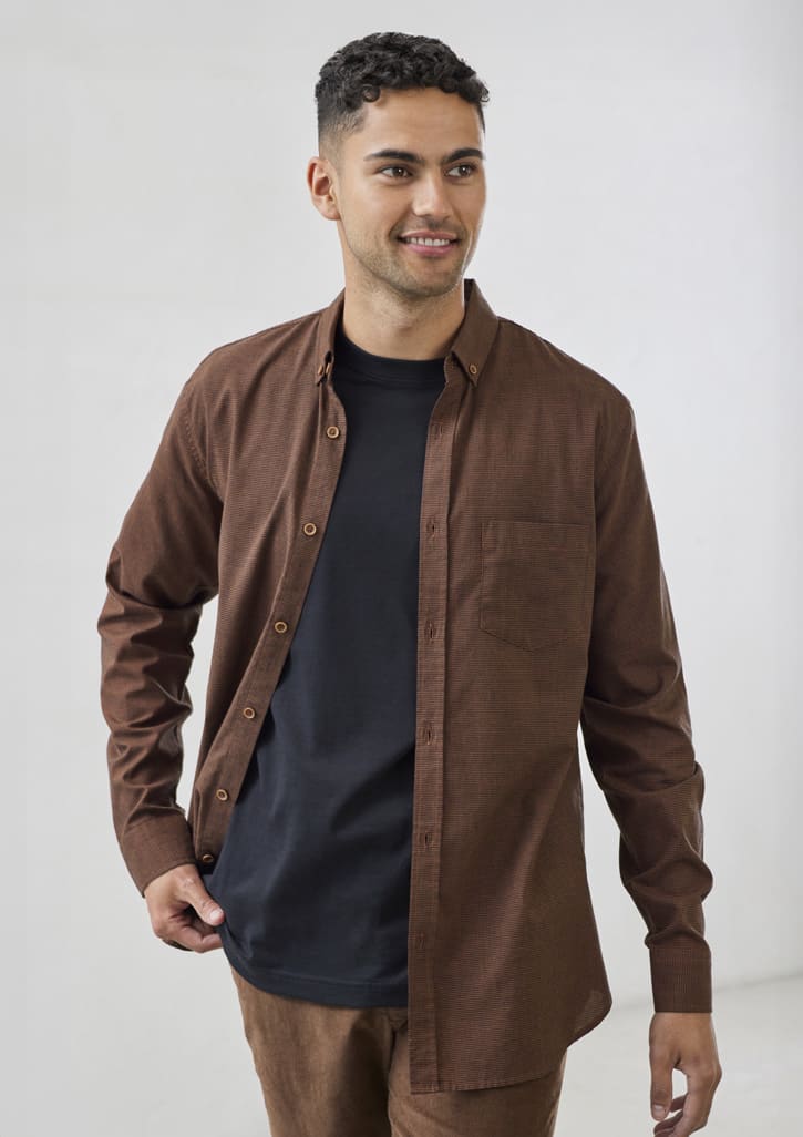 A brown long sleeve button-up shirt with a pocket, worn over a black T-shirt, featuring a logo.