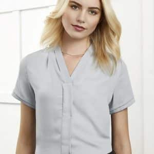 A light blue women's button-up shirt with short sleeves, featuring a subtle collar and a logo.