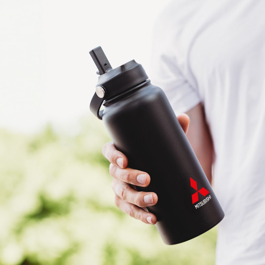A black drink bottle with a straw lid, held by a person, featuring a logo.