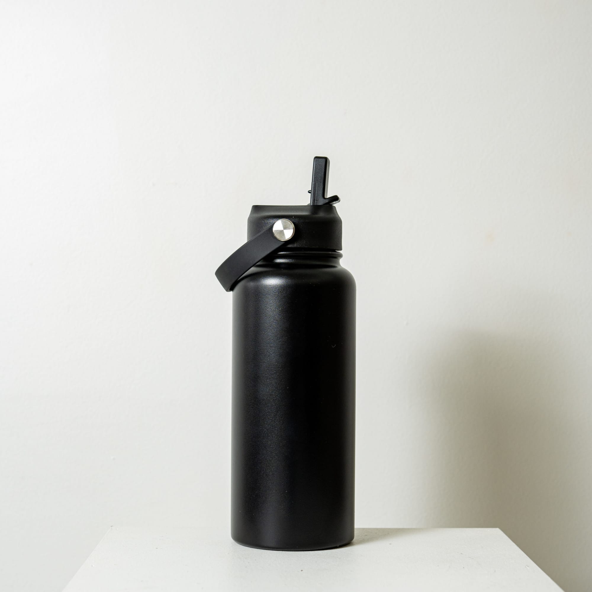 A drink bottle with a sleek black finish, featuring a lid and a handle for easy carrying.