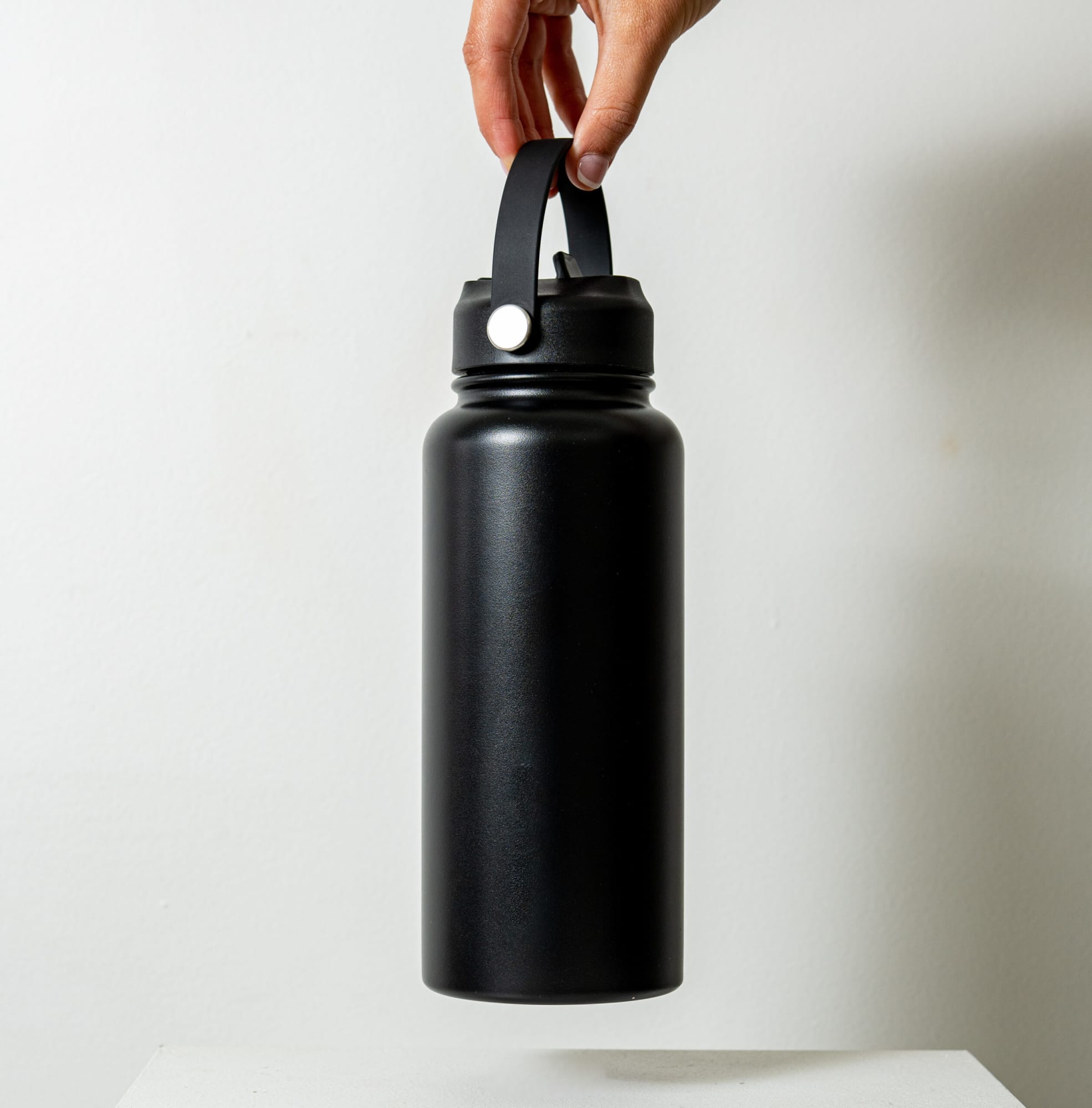 A drink bottle with a black matte finish and a sturdy handle, featuring a simple design and a logo.