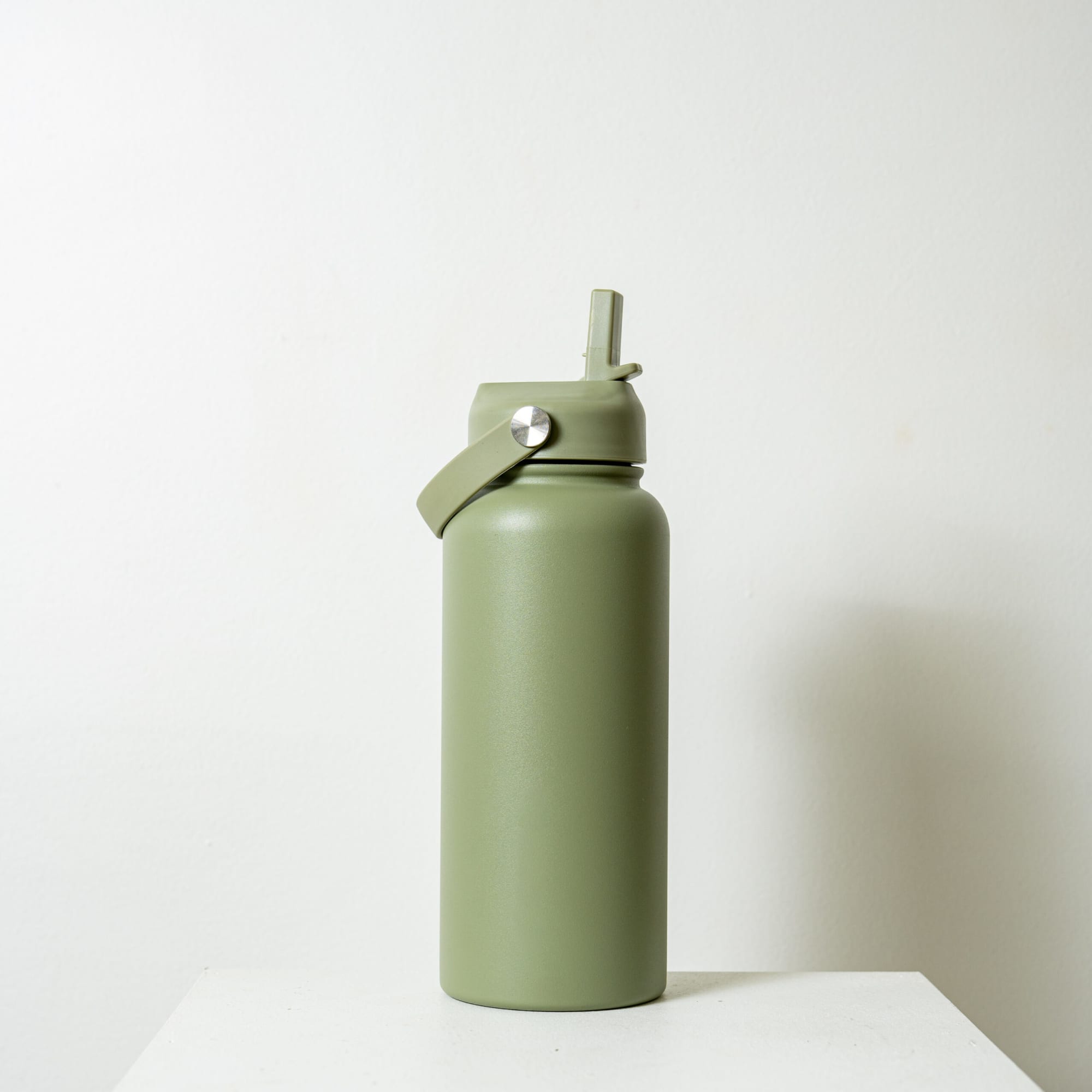A drink bottle in olive green with a screw top and spout, featuring a metal logo on the side.