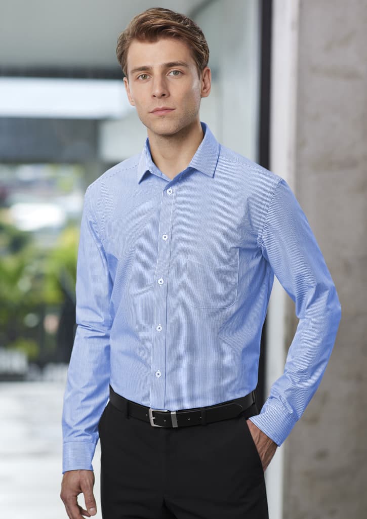 A blue long sleeve button-up shirt worn by a model, featuring a pocket and a logo.