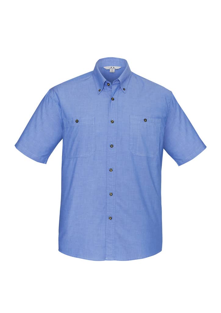A blue short sleeve chambray button-up shirt featuring two chest pockets and a logo on the collar.