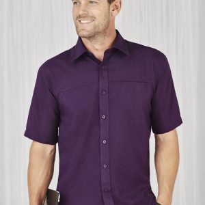 A plain short sleeve shirt in a rich purple colour with a button-up front and a pocket, featuring a logo.