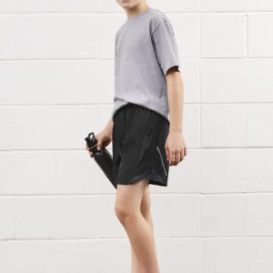A boy is wearing grey sports shorts and a grey t-shirt, holding a drink bottle. The shorts are black in colour.