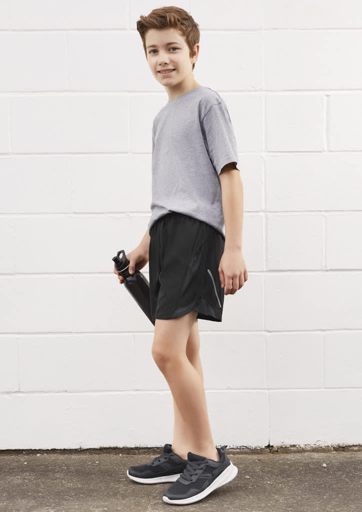 A boy is wearing grey sports shorts and a grey t-shirt, holding a drink bottle. The shorts are black in colour.