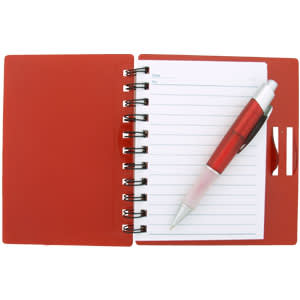 A red notepad with lined pages, spiral binding, and a pen resting on top. The cover features a slot for cards.