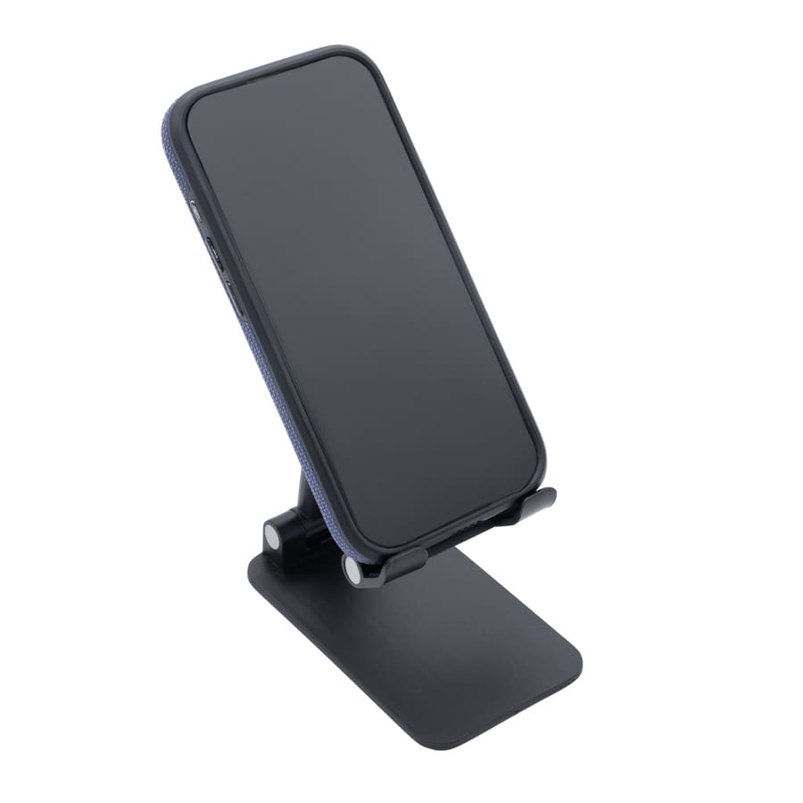 A black folding desktop mobile phone stand holding a smartphone, positioned on a desk near a computer keyboard.