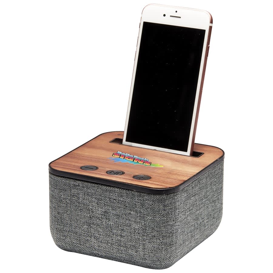 A Bluetooth speaker with a grey fabric exterior and wooden top, featuring a slot for a smartphone.