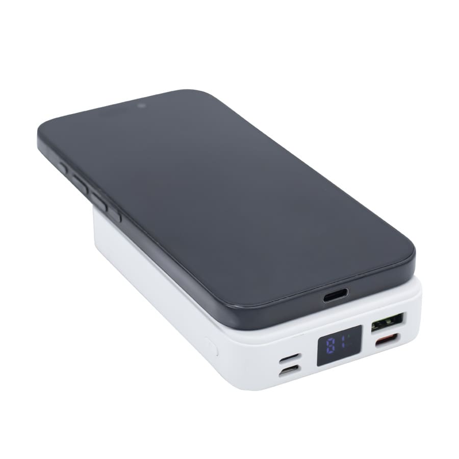 A black smartphone placed on a white Turbo 5000mAh wireless charging power bank with visible ports and a display.