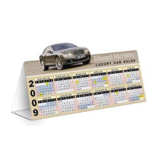 A table tent calendar featuring a luxury car image at the top and monthly calendars below, in yellow and white colours.