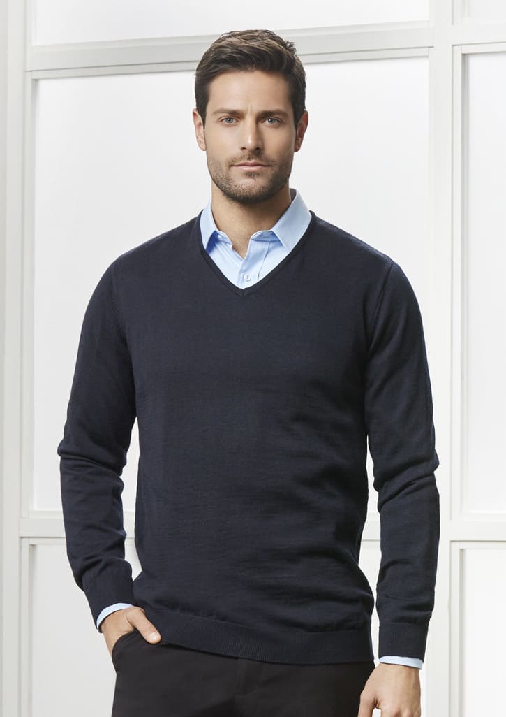 A navy blue pullover sweater with a V-neck, worn over a light blue shirt. The model stands against a bright background.
