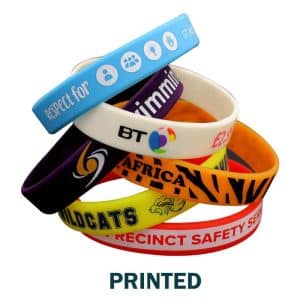 A collection of printed silicone wristbands in various colours, featuring different logos and designs.