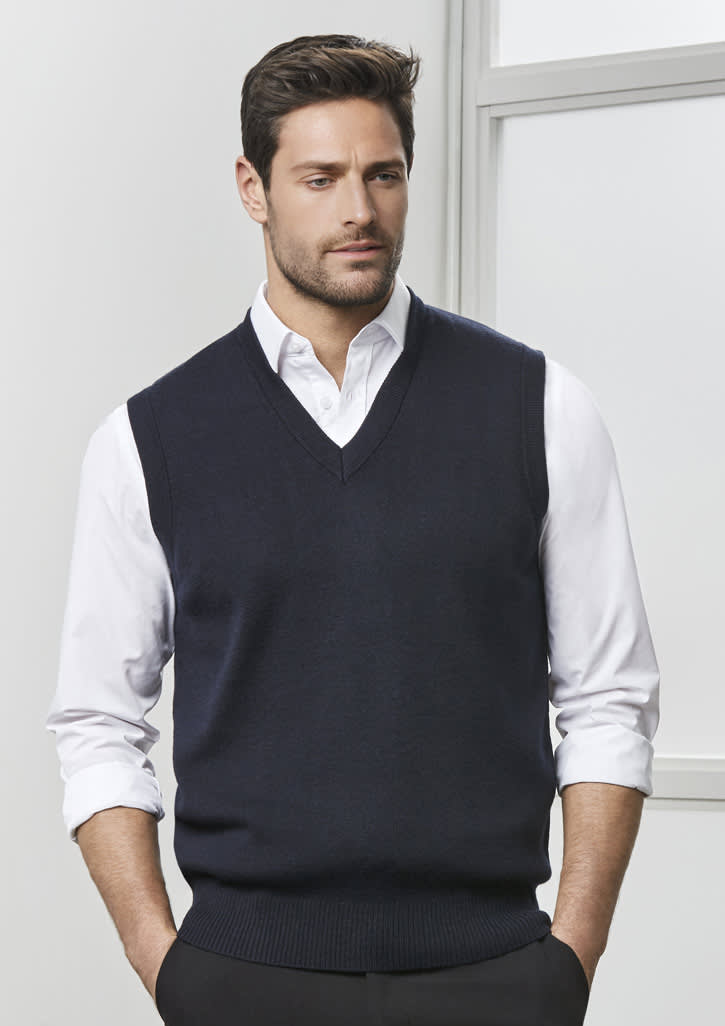 A navy men's woolmix knit vest with a V-neck design, worn over a white shirt. The model stands against a neutral background.