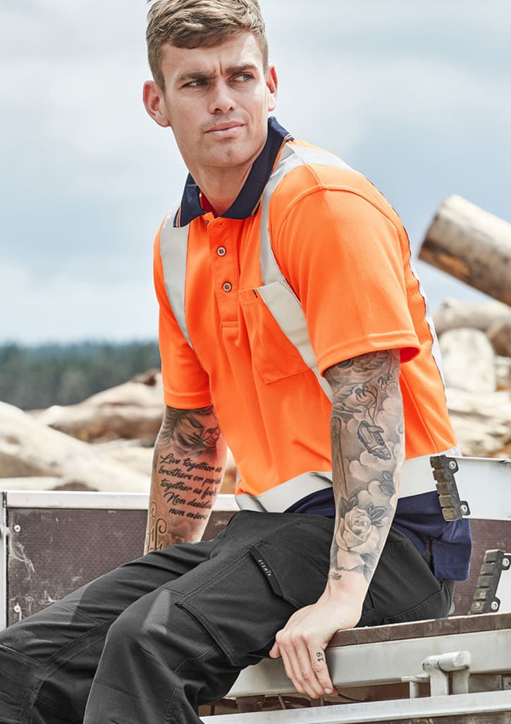 Hi-vis spliced short sleeve polo in bright orange with shoulder taping, featuring a model with tattoos seated outdoors.