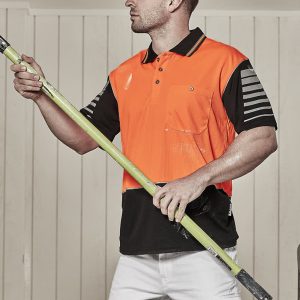 A man wearing an orange and black short sleeve polo shirt stands holding a green pole. The shirt has a logo.