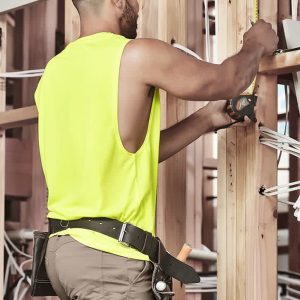 A sleeveless high-visibility yellow tee worn by a man working on a construction site, measuring with a tool.