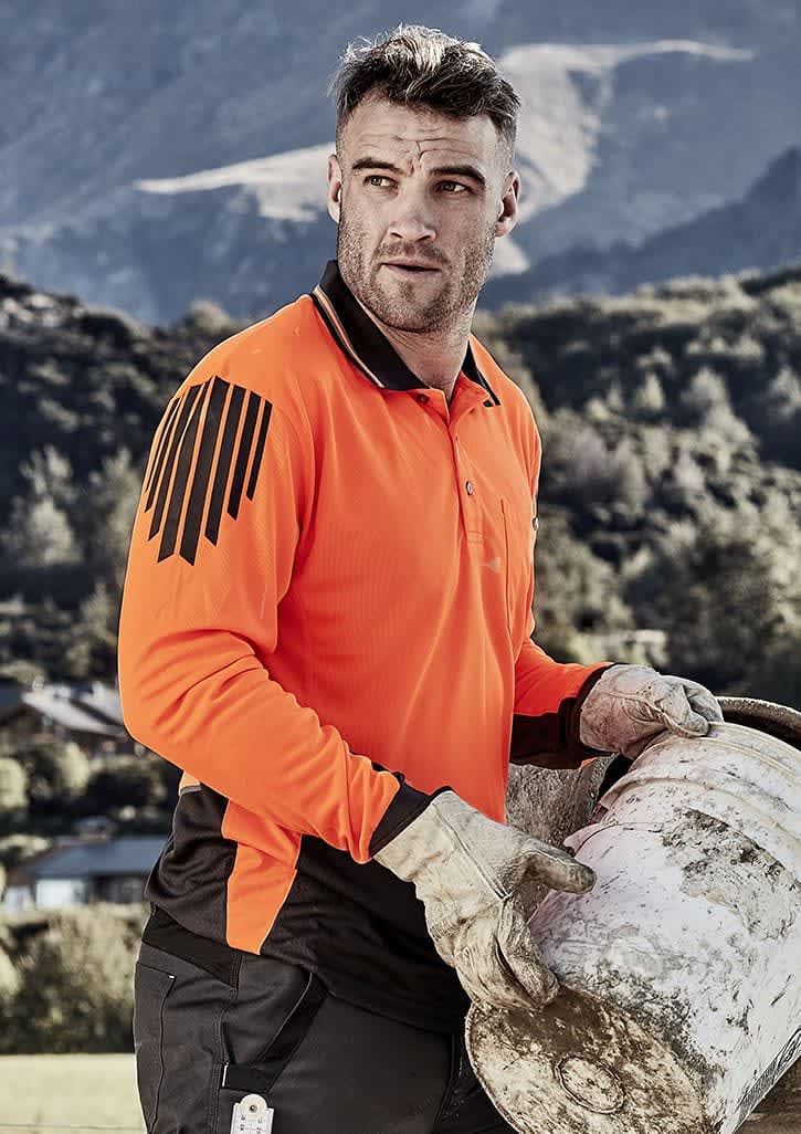 An orange and black long sleeve polo shirt featuring a logo, worn by a man carrying a bucket outdoors.
