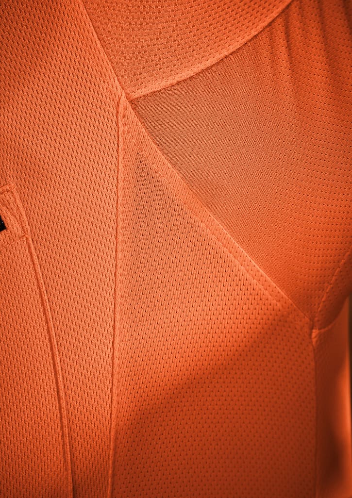 An orange short sleeve polo shirt with a textured fabric, featuring a logo on the chest.