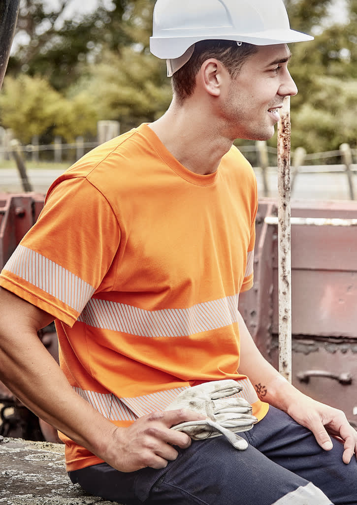An orange hi-visibility cotton tee with segmented reflective tape, worn by a man in a hard hat, sitting outdoors.