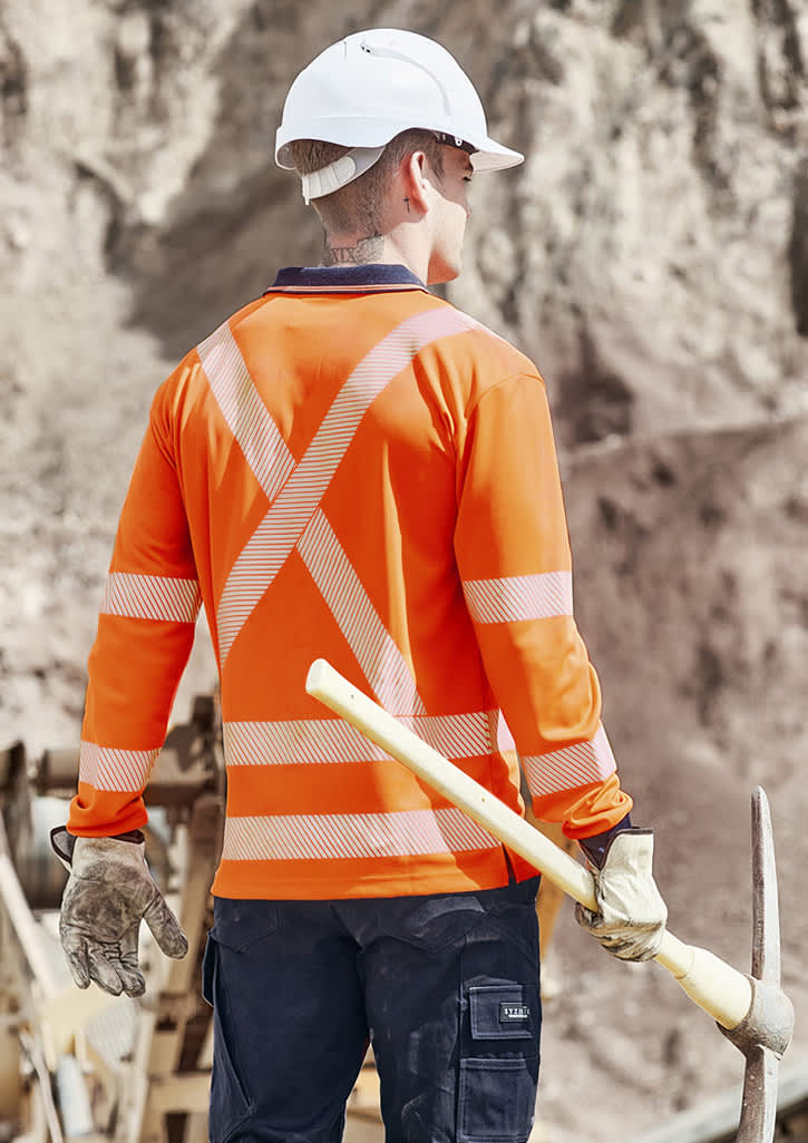 A long sleeve polo shirt in hi-vis orange with reflective stripes, worn by a worker on a construction site.
