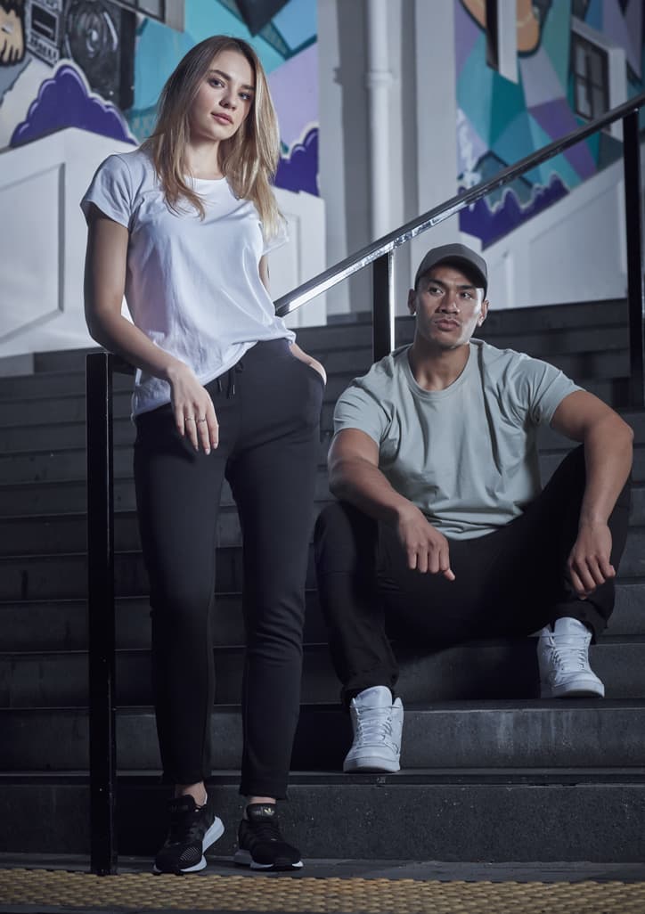 A woman in a white T-shirt and a man in a grey T-shirt sit on black stairs, both wearing casual athletic attire.