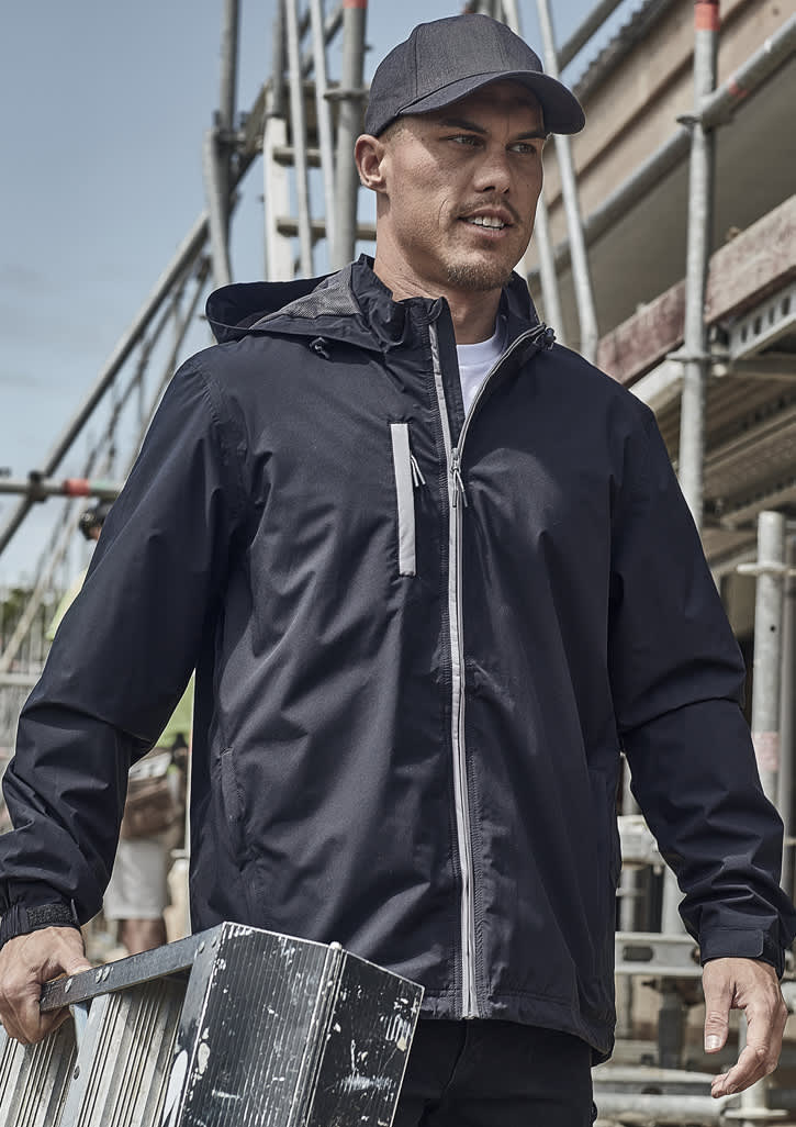 A man wearing a black unisex packable rain jacket, holding a metal ladder, with construction scaffolding in the background.