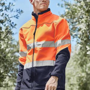 A hi-vis softshell jacket in bright orange and navy, featuring reflective stripes and a zipped front, worn by a model outdoors.