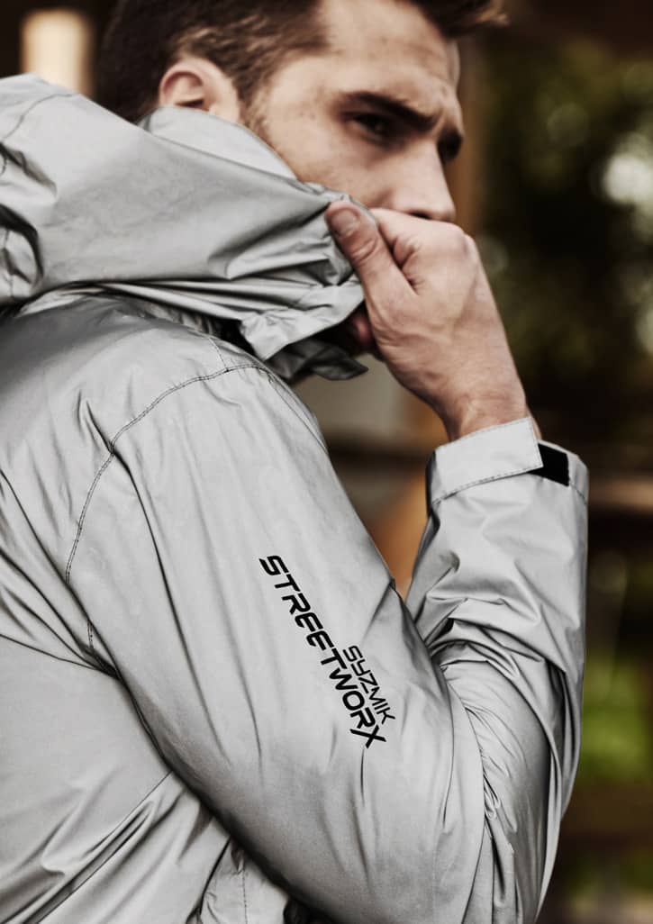 A reflective grey waterproof jacket with a logo, featuring a close-up of a model wearing it.