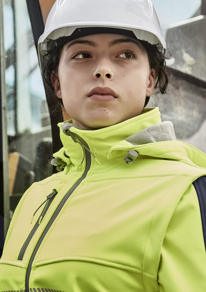 A women's bright yellow stretch softshell jacket with a hood, worn by a person in a hard hat.