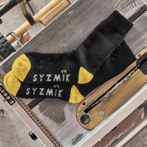 A pair of black and yellow work socks laid on a metallic surface, featuring a logo.