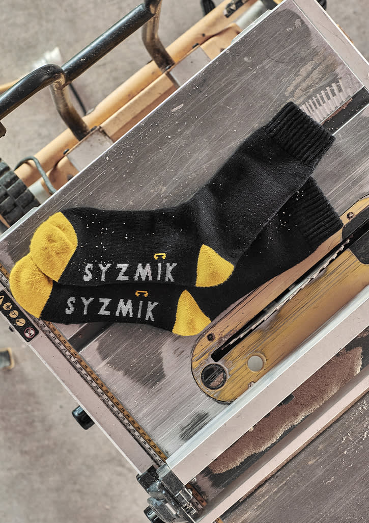 A pair of black and yellow work socks laid on a metallic surface, featuring a logo.