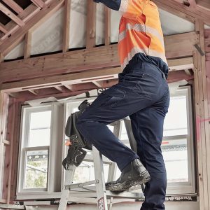 Men's cargo pant in navy, worn by a man on a ladder, working in a partially constructed building. The pants have pockets and a logo.